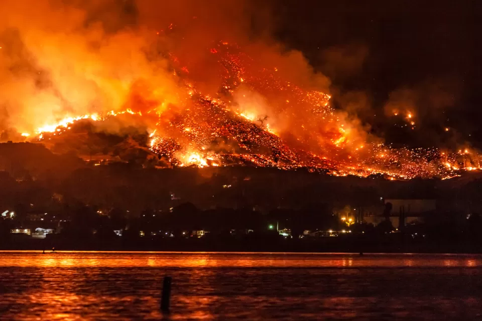 Wildfire burning at night on hillsides next to Lake Elsinore, California.